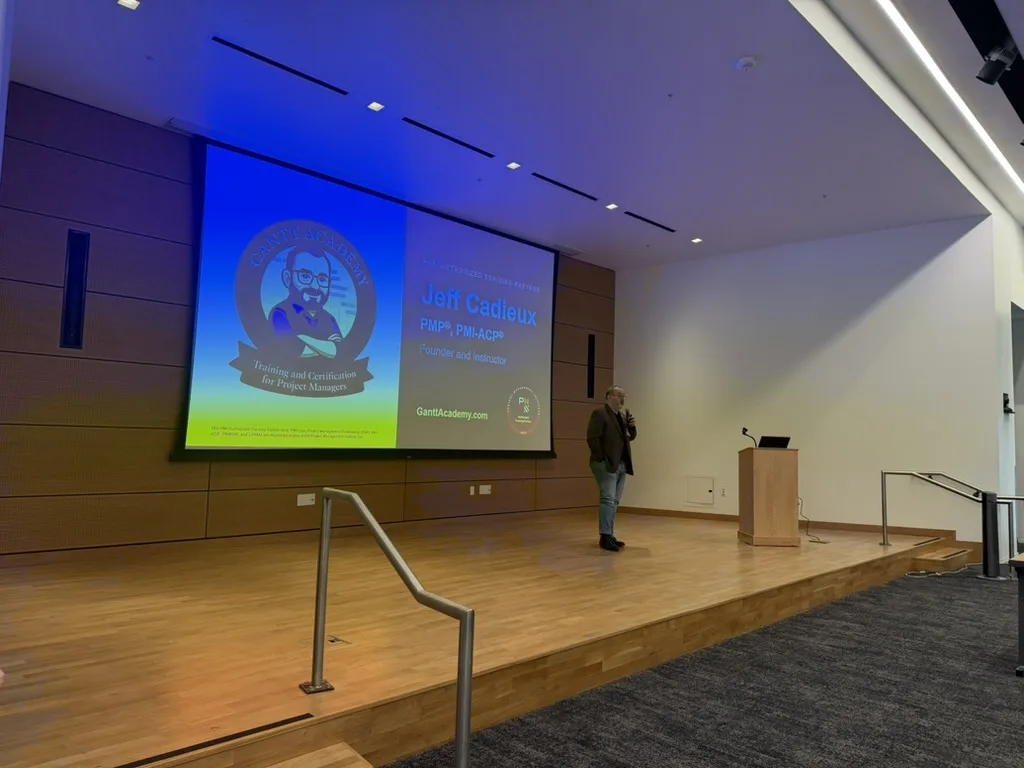 Jeff Cadieux speaking on stage at the PMI Silicon Valley 2026 Annual Symposium in Fremont, with the Gantt Academy title slide behind him